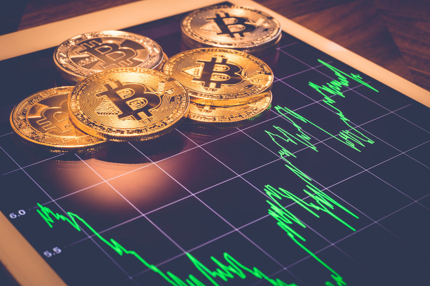 Cryptocurrency, focus Bitcoin on tablet screen that showing green price or stock market performance graph, light reflect with vintage filter. Decentralized, exchange digital money through blockchain.